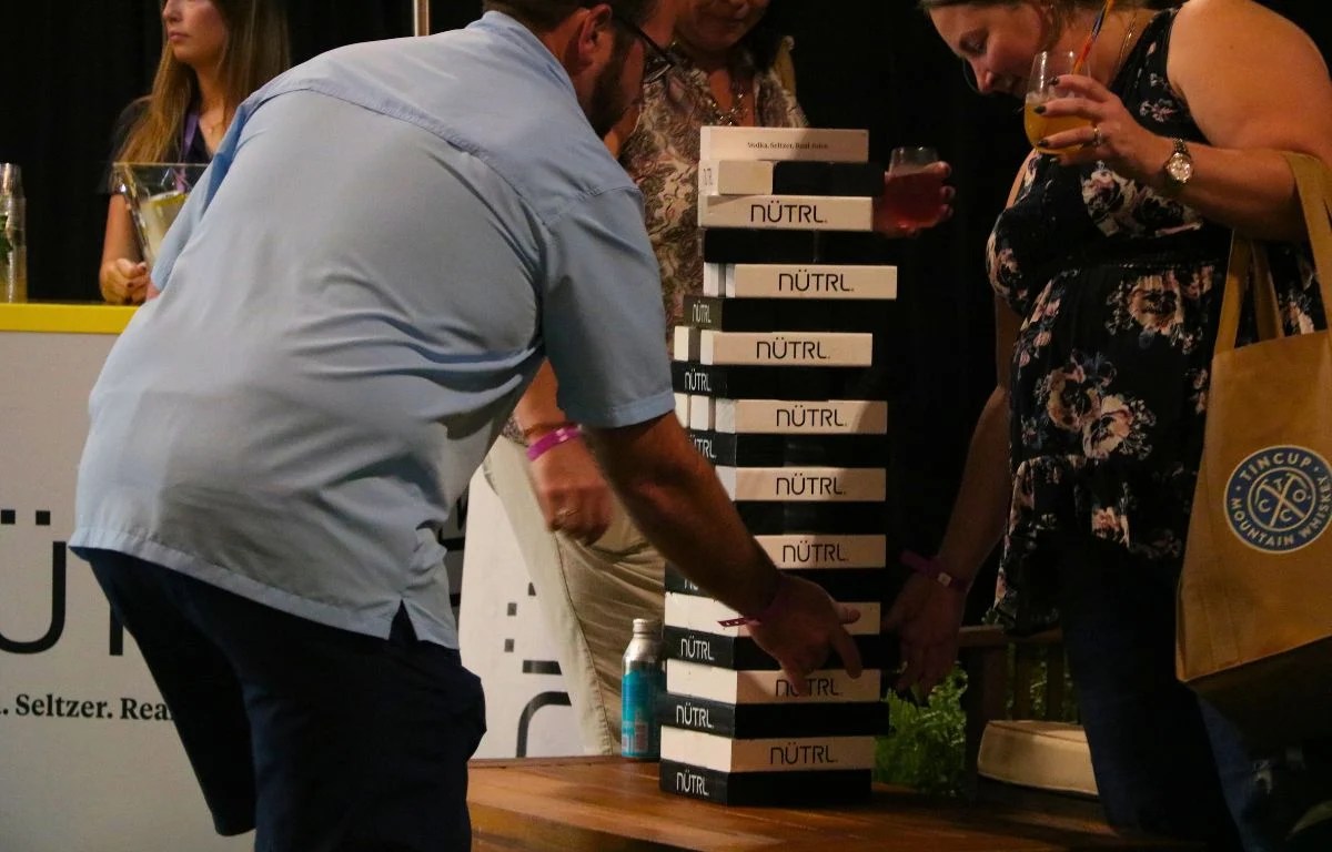 A man in a light blue shirt sets up a Jenga tower with black and white blocks.