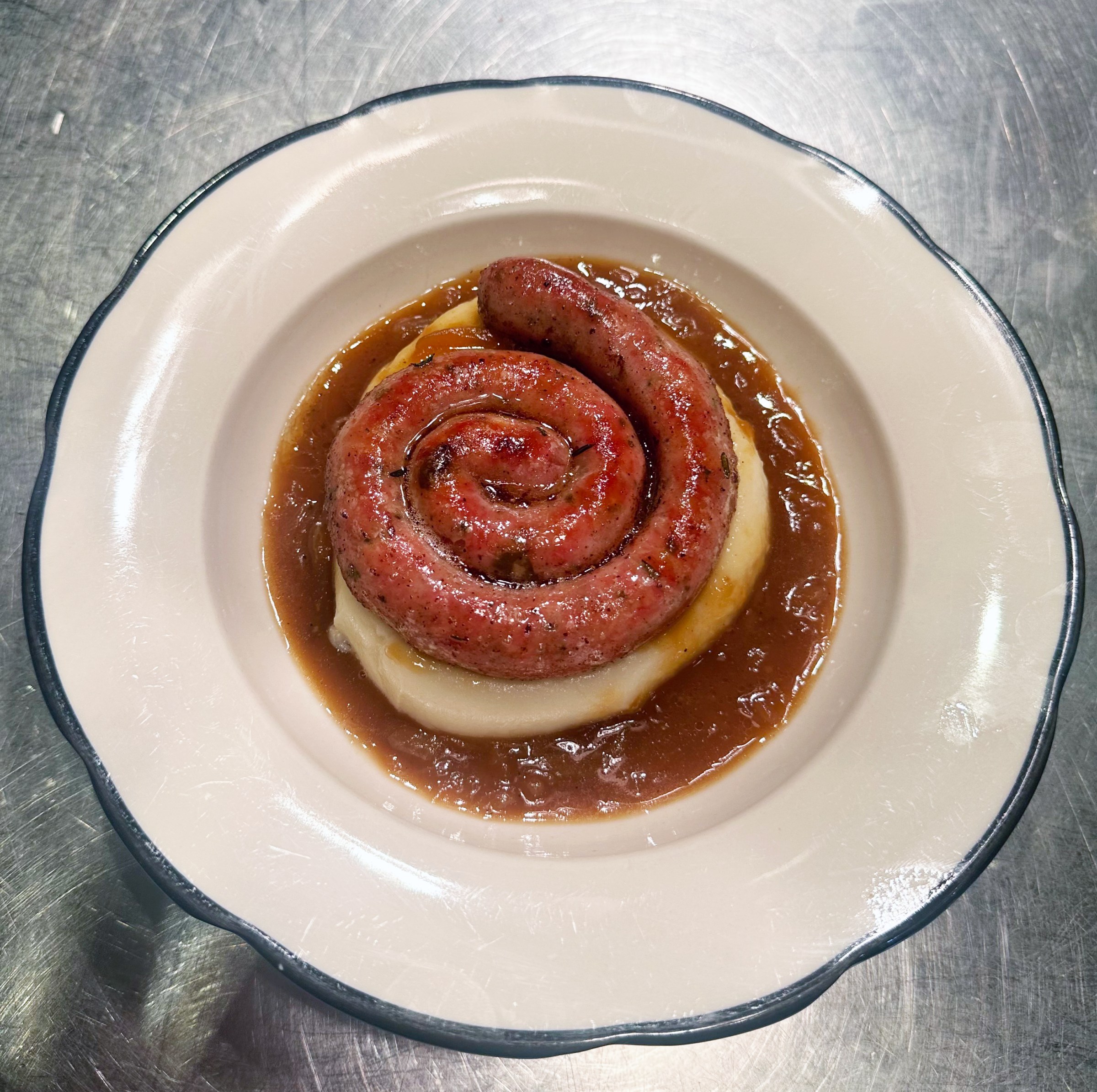 A curled sausage on a bed of mashed potato and gravy by chef George Dingle in San Francisco.