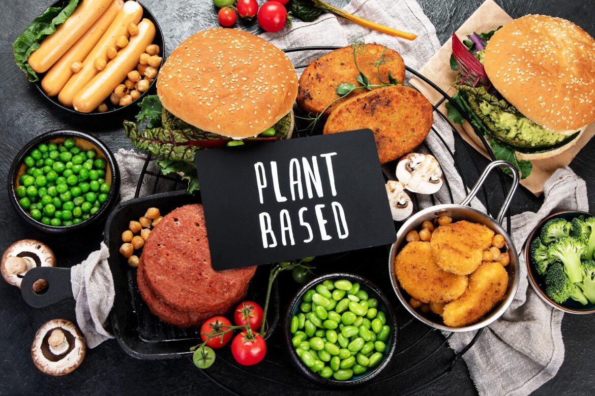 Which plant-based diet is healthiest and most sustainable Plant-based food concept-vegan burgers, sausages, vegetarian nuggets, fresh vegetables and sauces on a dark background. top view