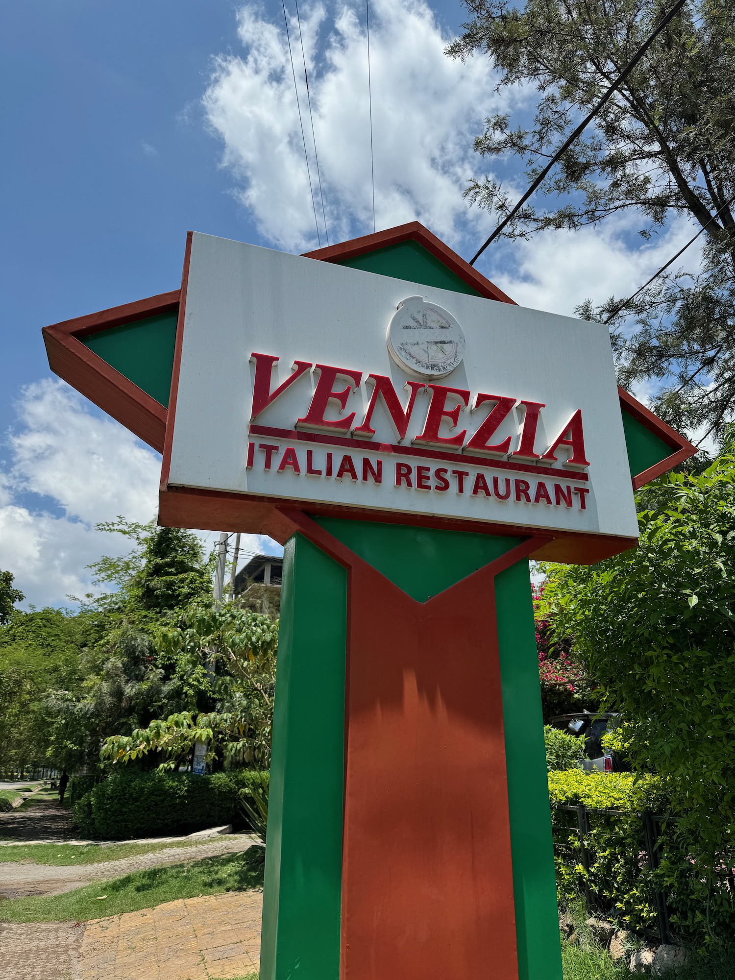 a sign outside with trees and blue sky