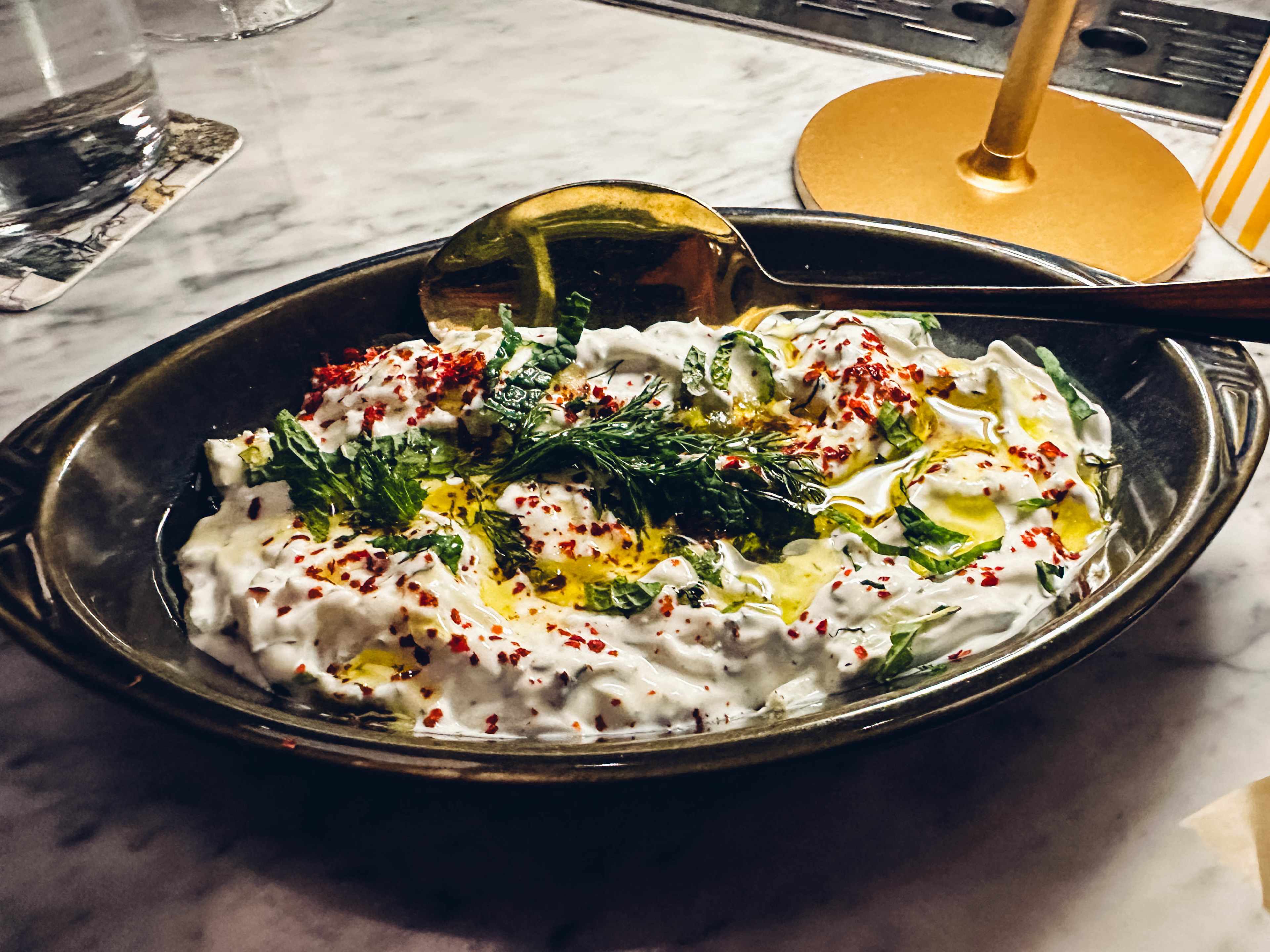 A small bowl of tzatziki topped with dill.