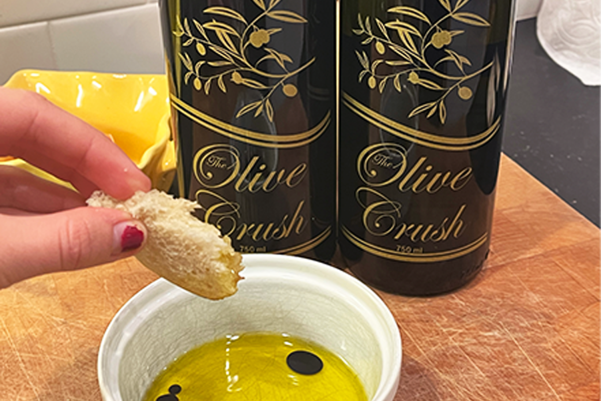 Madelyn Rolland, a senior at Carlmont, dips a piece of bread into The Olive Crush's olive oil and balsamic vinegar. "The whole goal at The Olive Crush is to be able to spread information so that everybody can cook and make great food at home. It all starts with healthy great ingredients," said Mike Fitch.
