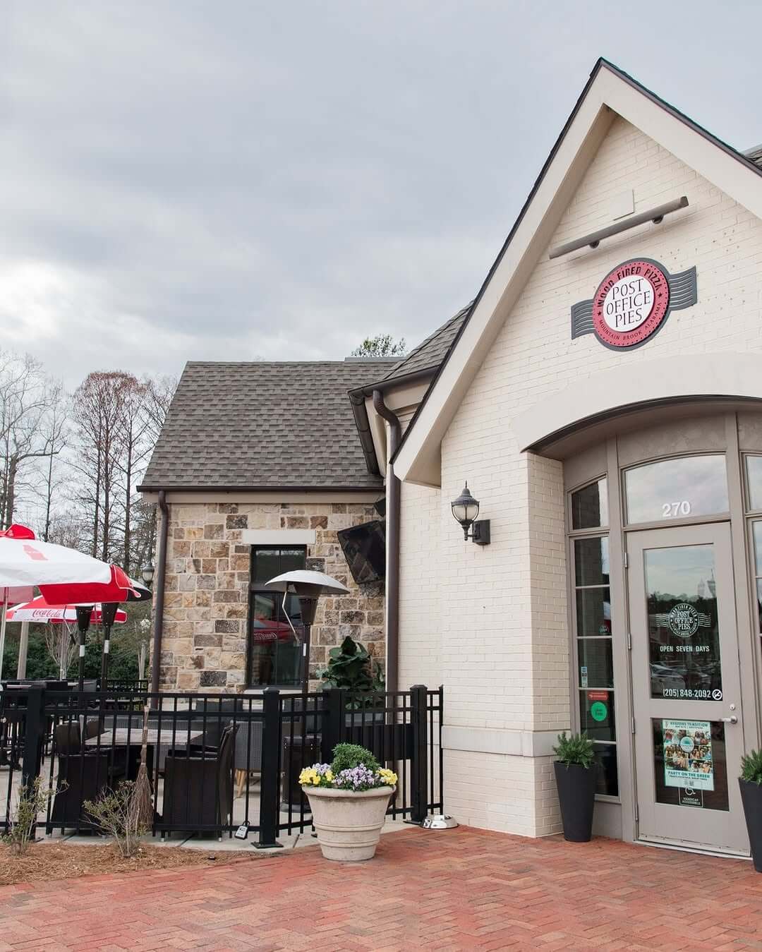 7 Beloved BHAM Restaurants We'll Miss - 3 A restaurant with a sign reading "Post Office Pies" above the entrance, outdoor seating area with umbrellas, and potted plants near the door.