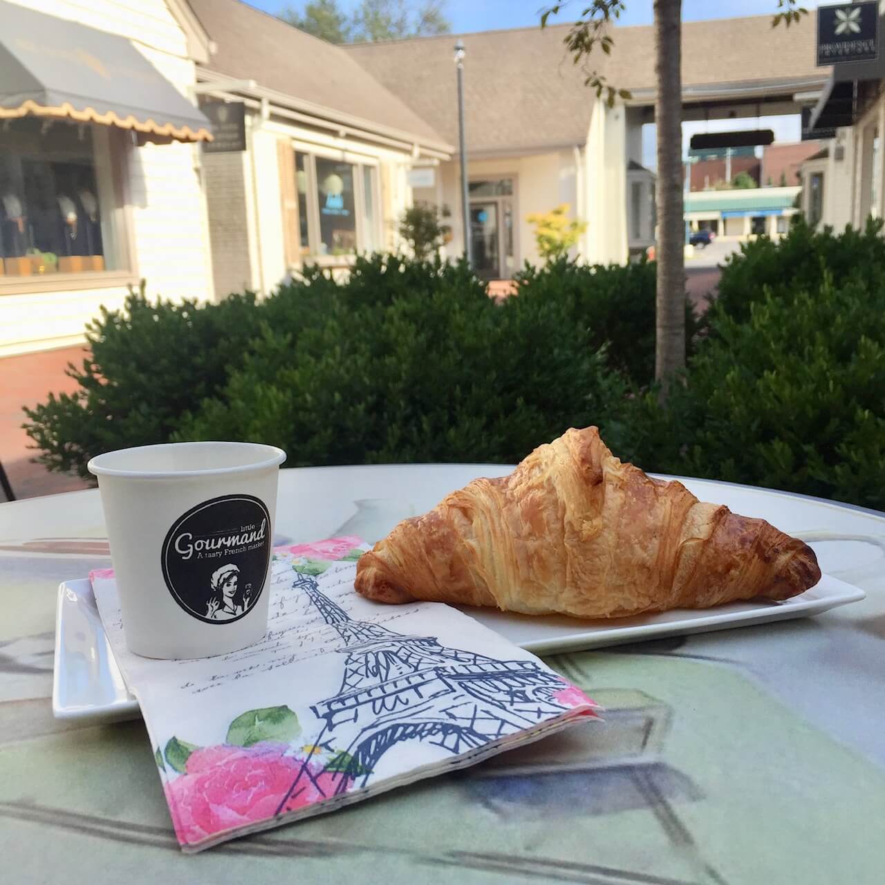 Croissant and a cup of coffee outside of Little Gourmand