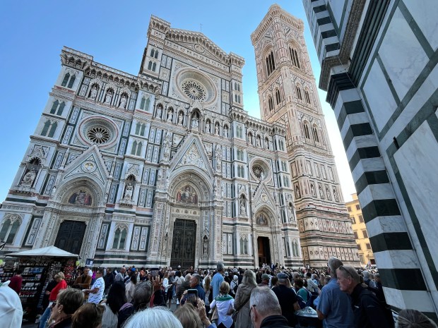 An ornate marble facade of a church. There is a big crowd of people in front of it