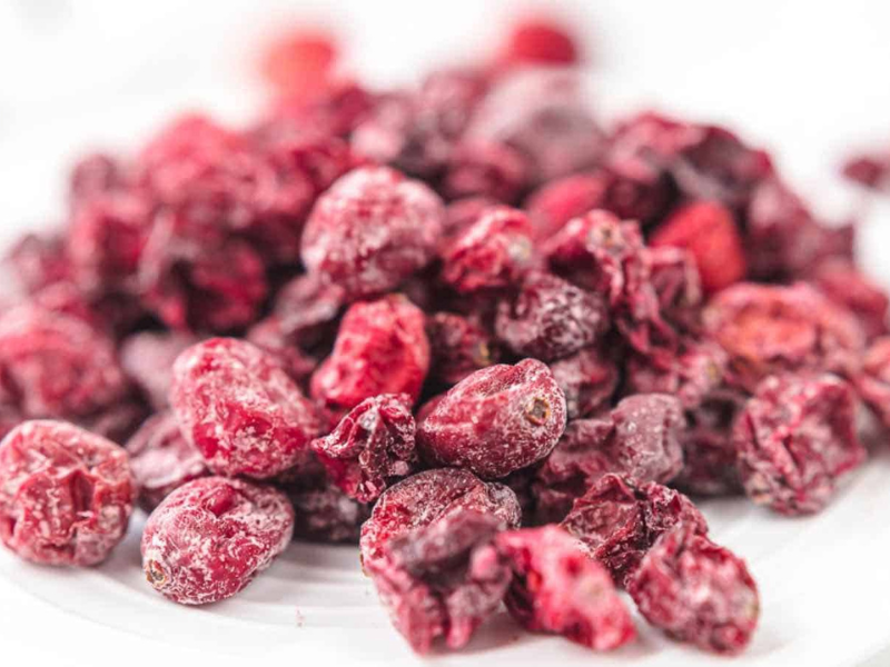 A close-up view of a pile of dried cranberries on a white surface.