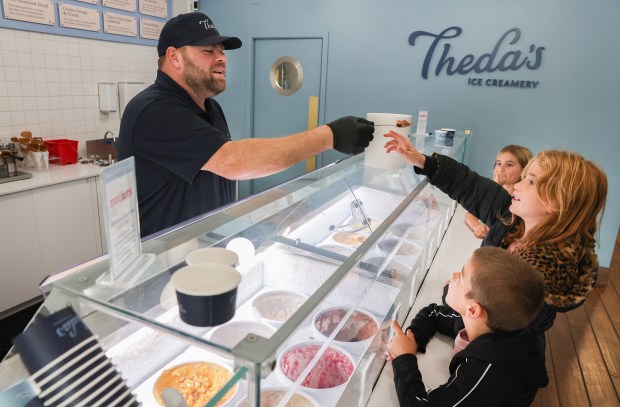 Trevor Terrill, left, serves ice cream samples to Rex, 6,...