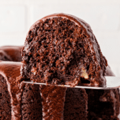 a close up of a single slice of a triple chocolate bundt cake topped with homemade chocolate buttercream frosting on a serving spatula