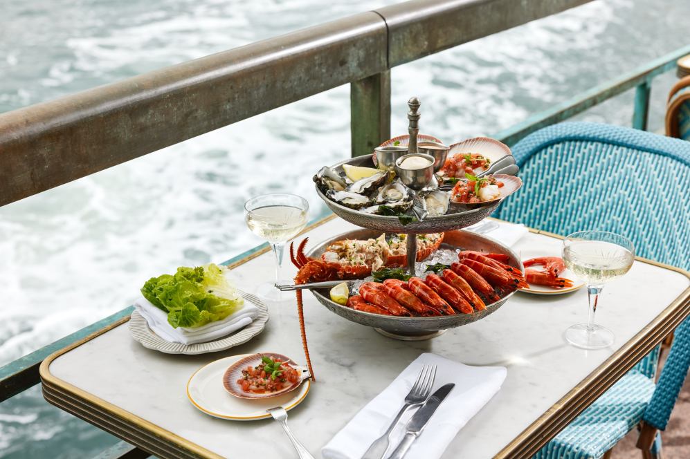 Seafood platter on two person table by water's edge. 