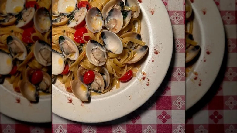 Fettuccine with clams and cherry tomatoes in plate plate on red and white checkerboard tablecloth