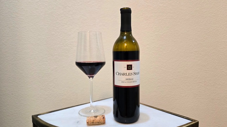 Charles Shaw Shiraz next to a glass filled with wine and a cork