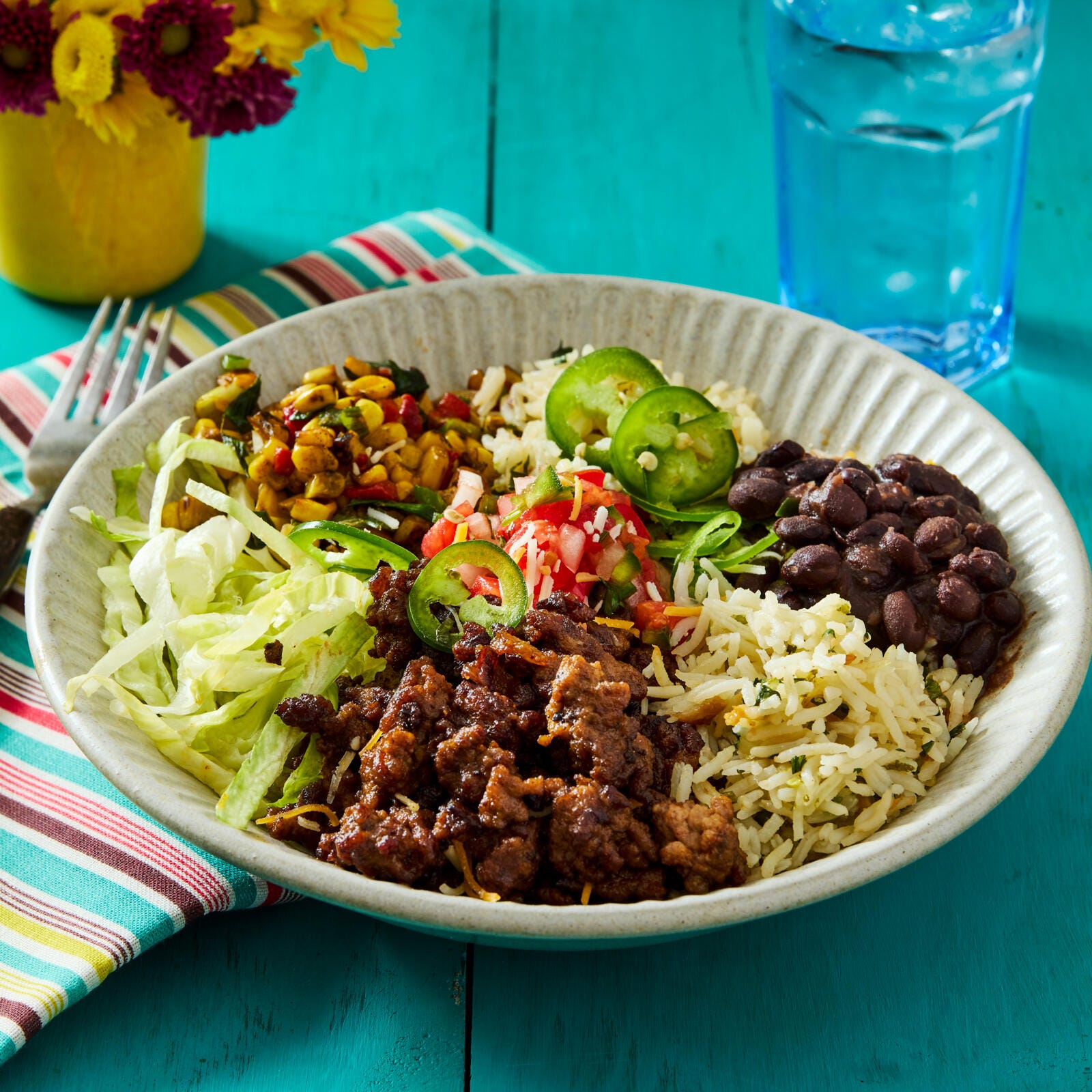 bowl of mixed ingredients including rice meat beans and fresh vegetables