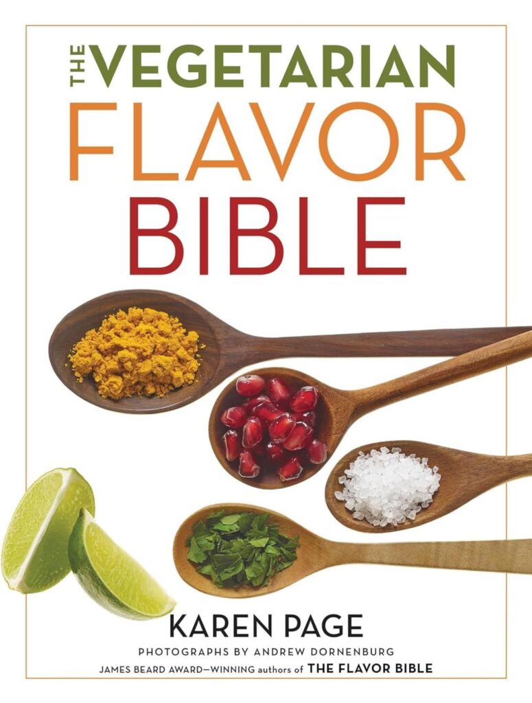 A cookbook cover for the book The Vegetarian Flavor Bible by Karen Page. It has a white background shows four wooden spoonfuls of ingredients: an orange powder, pomegranate seeds, sea salt, and chopped parsley, with lime wedges on the side.
