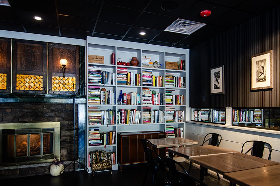 A restaurant dining room features shelves of cookbooks and a working fireplace.