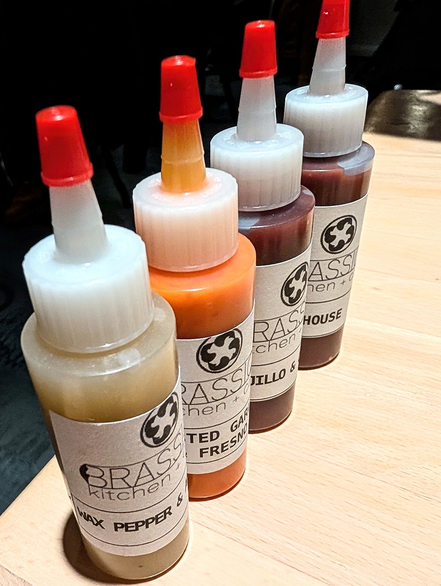 A lineup of four mini hot sauce bottles with Brassica labels.