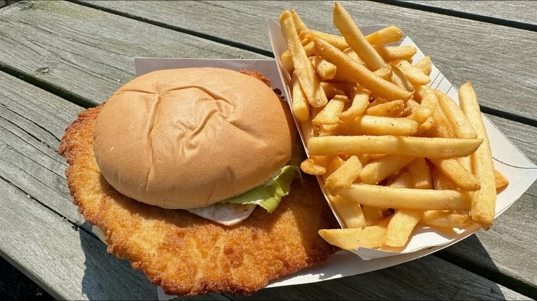 Pork Tenderloin Sandwich : Crispy breaded pork tenderloin sandwich served with lettuce and fries, an American Midwest favorite known for its oversized cutlet and crunchy coating.