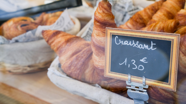 croissants in a case with a price sign in front