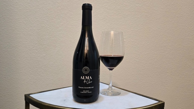 Alma de Uco Grand Assemblage and glass on a table with a white background