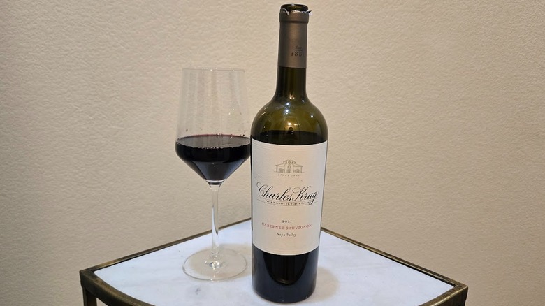 Charles Krug Napa Valley Cabernet Sauvignon with a wine glass on a white table and a white background