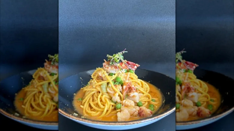 Pasta in broth topped with seafood in blue dish