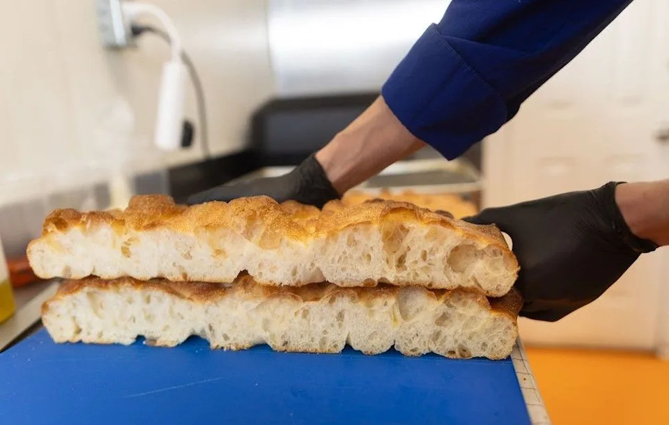 Fenoma Kitchen proprietor Roman Koval cuts fresh schiacciata bread for his decadent Italian sandwiches. Brent Calver/Postmedia