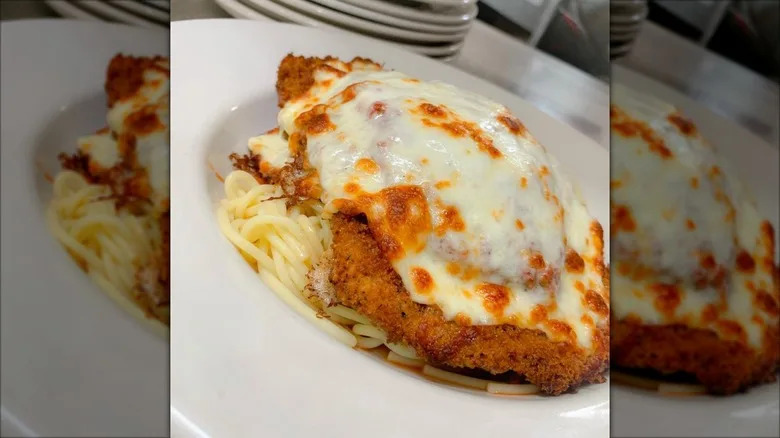 Chicken parm on bed of spaghetti on white plate