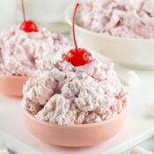 two bowls of cherry fluff salad topped with maraschino cherries