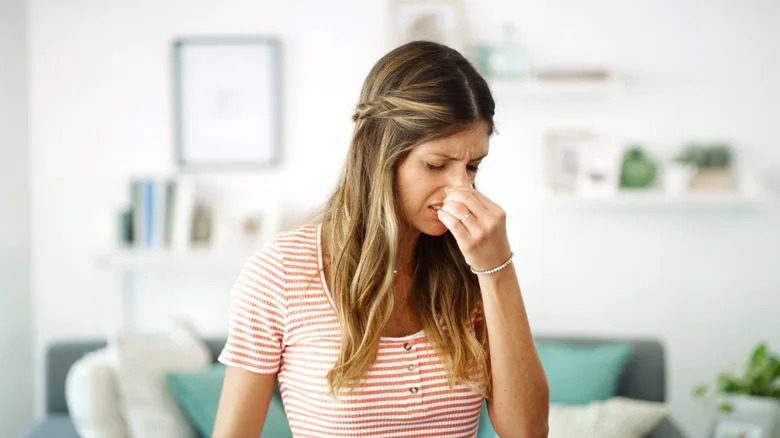 Bad smell, woman pinching her nose