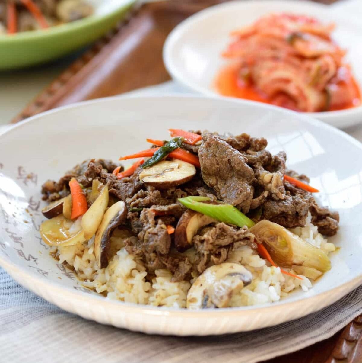 a white bowl with rice, sautéed beef, and vegetables