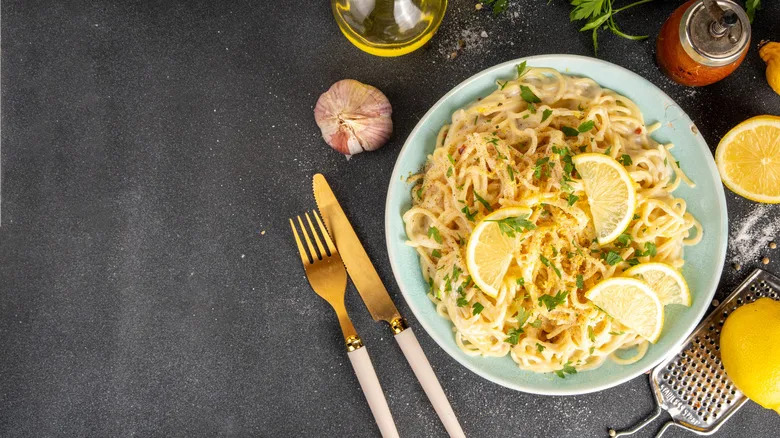 Blue bowl of pasta with lemon slices and parsley