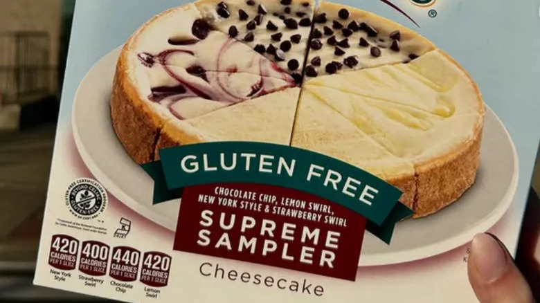 A hand holding a box of LiveGFree Gluten-Free Cheesecake Sampler