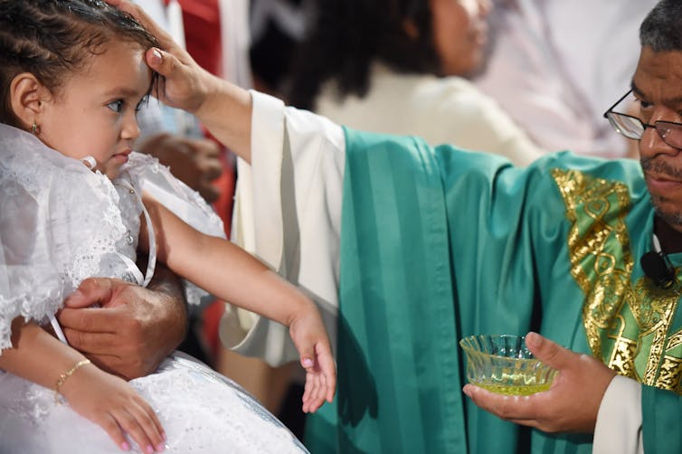 A child is annointed with oil during a Catholic ceremony.