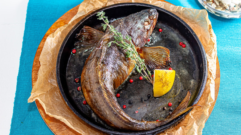 whole fish fried in cast iron pan with lemon