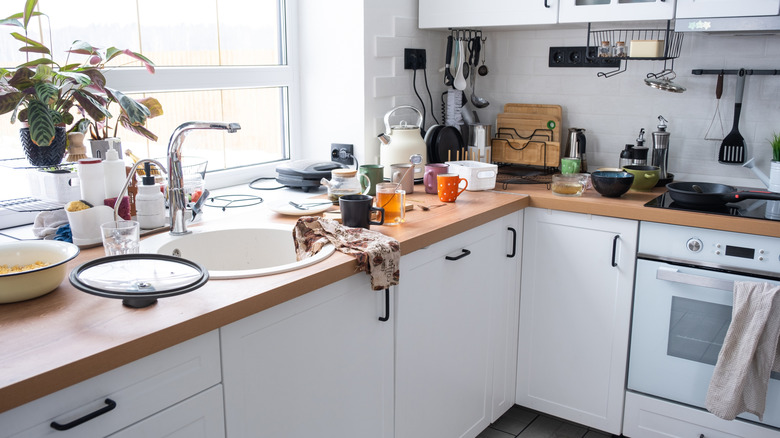 Close up of a cluttered kitchen counter with many things on it