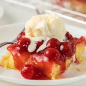 a close up of one piece of gluten-free cherry almond cake topped with a scoop of vanilla ice cream