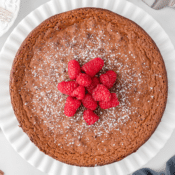 gluten free flourless chocolate cake topped with fresh red raspberries and powdered sugar