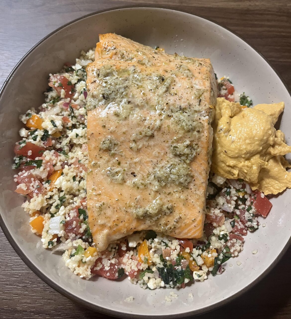 Salmon on a bed of couscous salad with hummus