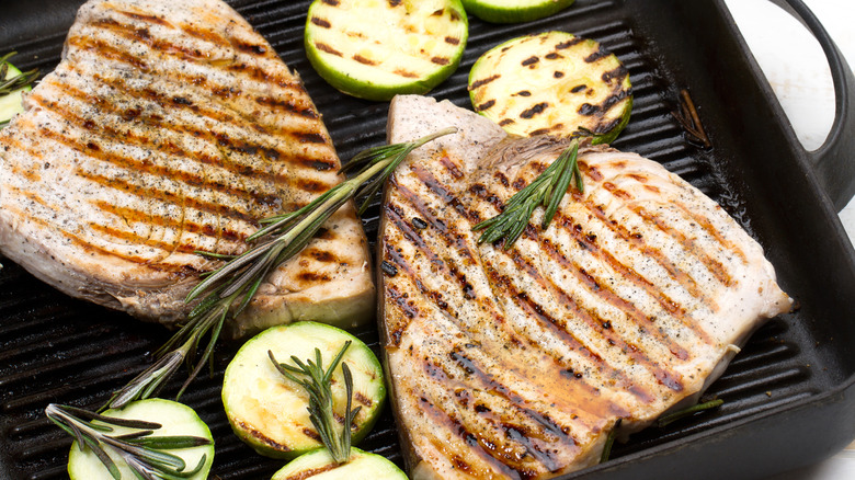 Two grilled swordfish steaks with rosemary on them