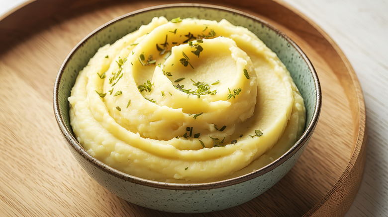 Bowl of creamy mashed potatoes with herb garnish
