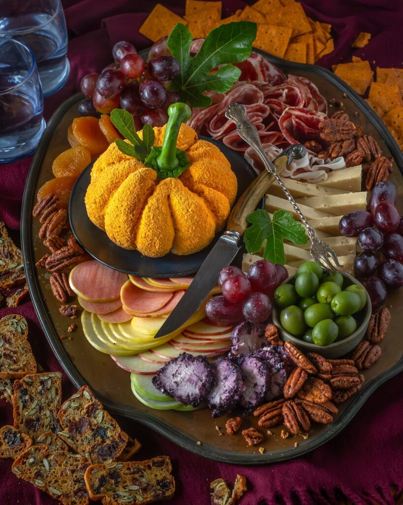 Fall themed board with a pumpkin shaped cheddar and apple cheeseball.