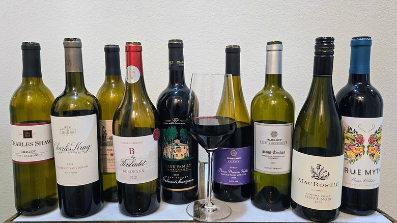 Bottles of red wine available at Trader Joe's and glass of wine