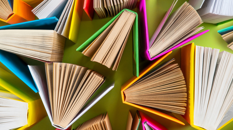 Colorful books propped up and open on green background