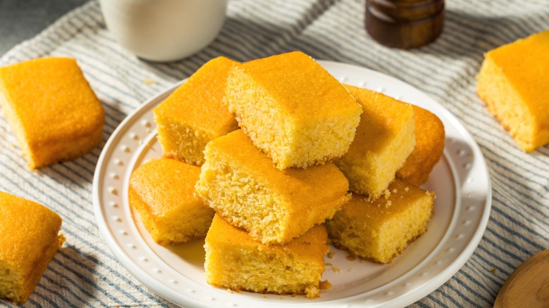 A glass plate of cornbread squares on a striped cloth