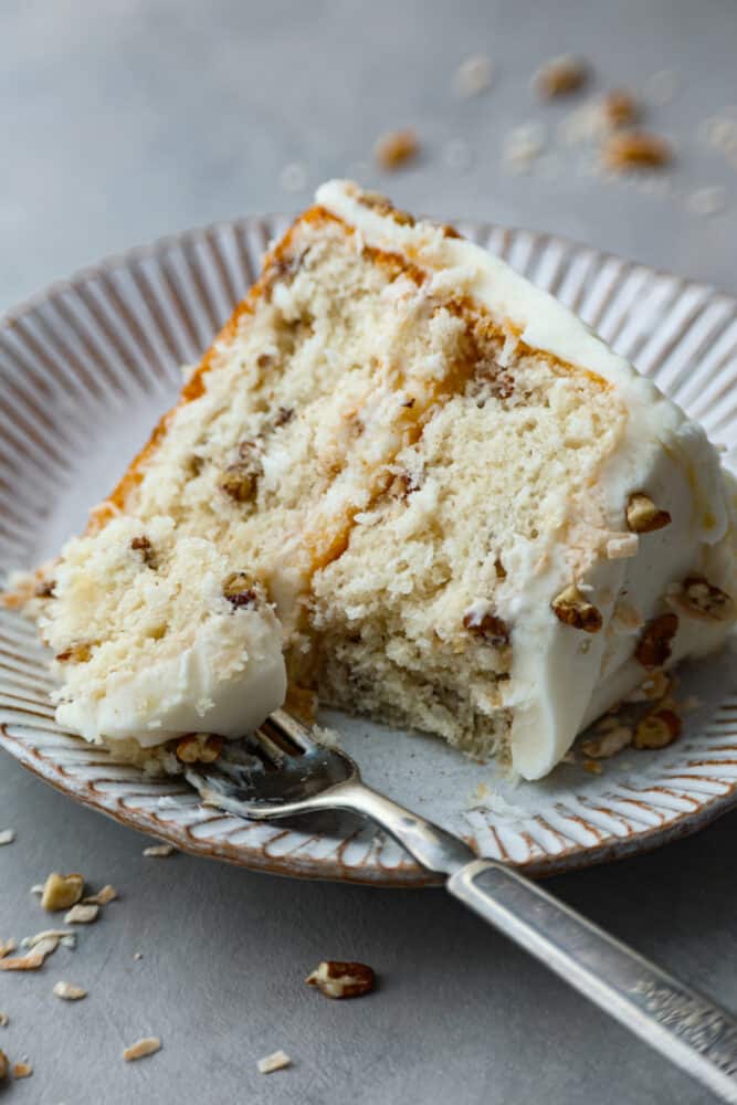 Take a bite of heaven with every forkful of this dreamy Italian cream cake. It's rich and nutty, covered with the most amazing cream cheese frosting! It's great for special occasions, but really, there's no wrong time to make it! Closeup of a slice of cake. A bite is taken out of it with a fork.