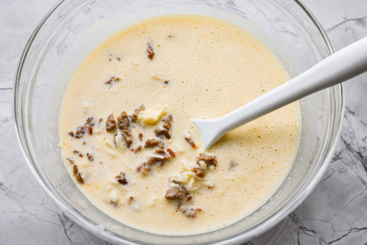 In a blender, add the eggs, cottage cheese, salt, pepper, and dried basil. Cooked sausage, sun-dried tomatoes, and shredded cheese added to the egg mixture.