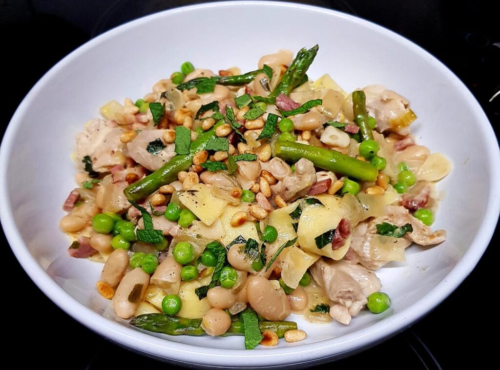 Chicken and Bacon Pappardelle with White Beans, Peas and Asparagus. White Wine Tarragon Sauce, Finished with Fresh Mint and Pine Nuts.