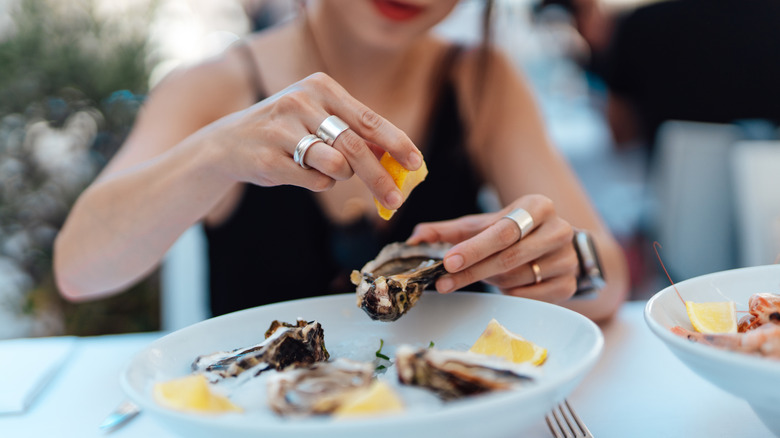 close up of woman eating oysters at outdoor restaurant.