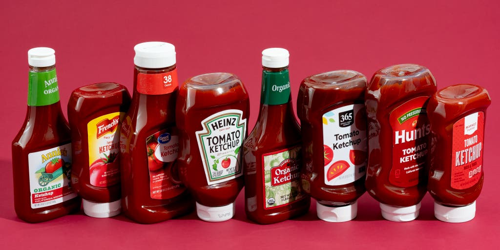 Several bottles of ketchup standing in a row.