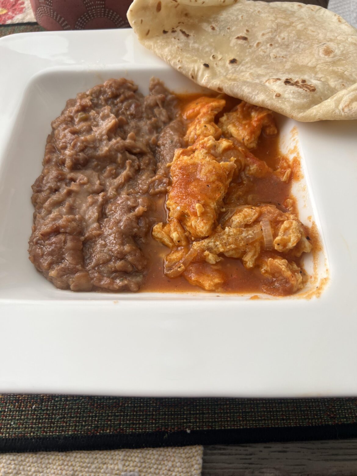 Huevos con chile rojo y frijoles fritos y tortillas de harina