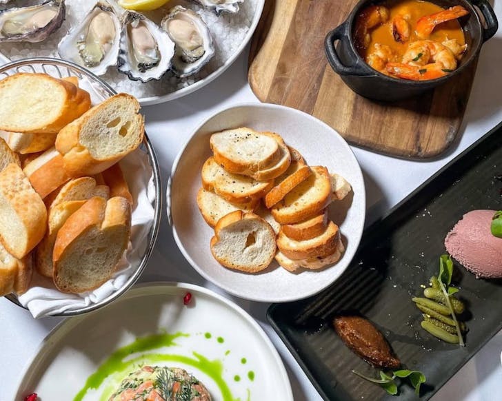 macleay st bistro flatlay of a menu prepared on a table, with oysters, bread and other french dishes